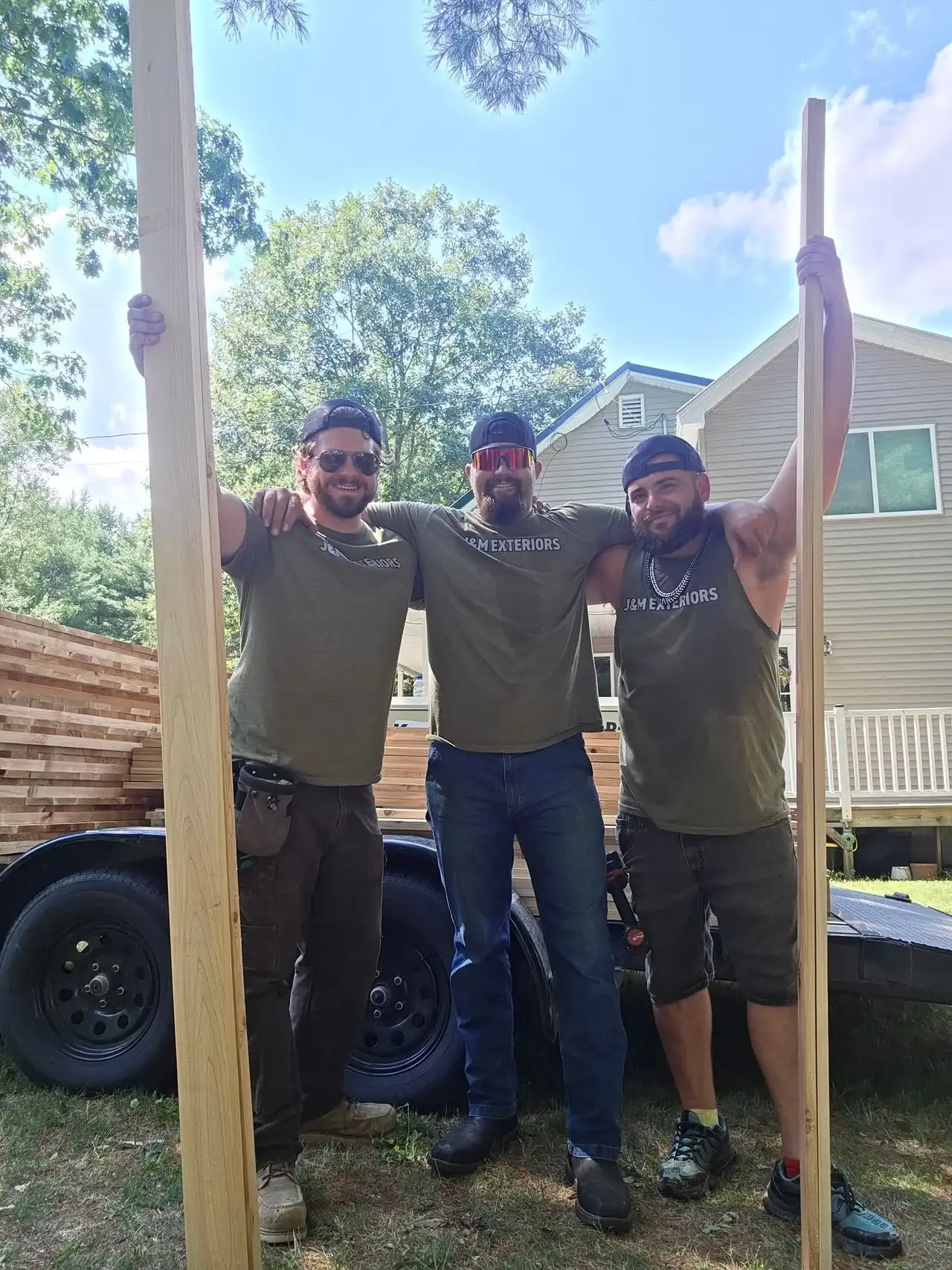 Three team members standing beside a wooden post