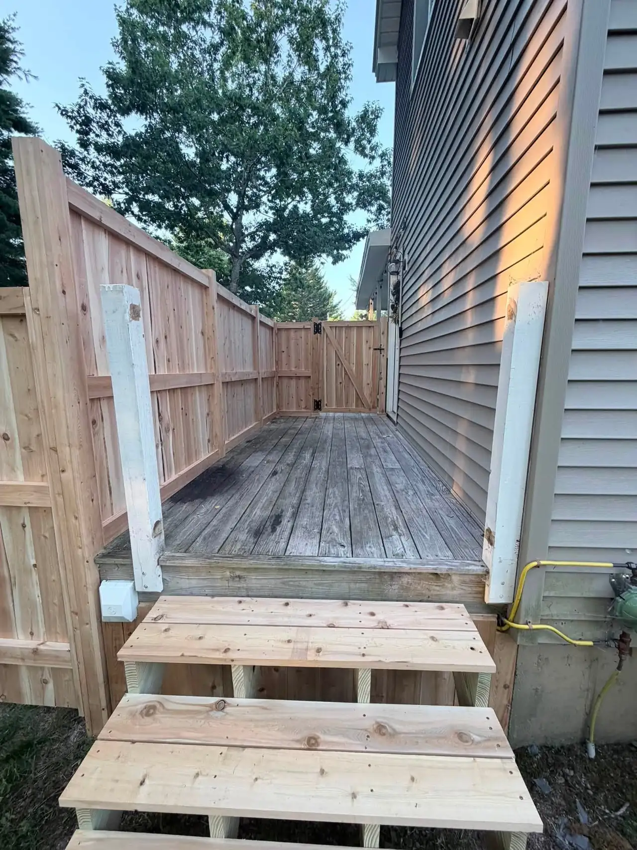 Wooden deck, steps, and privacy fence beside a home