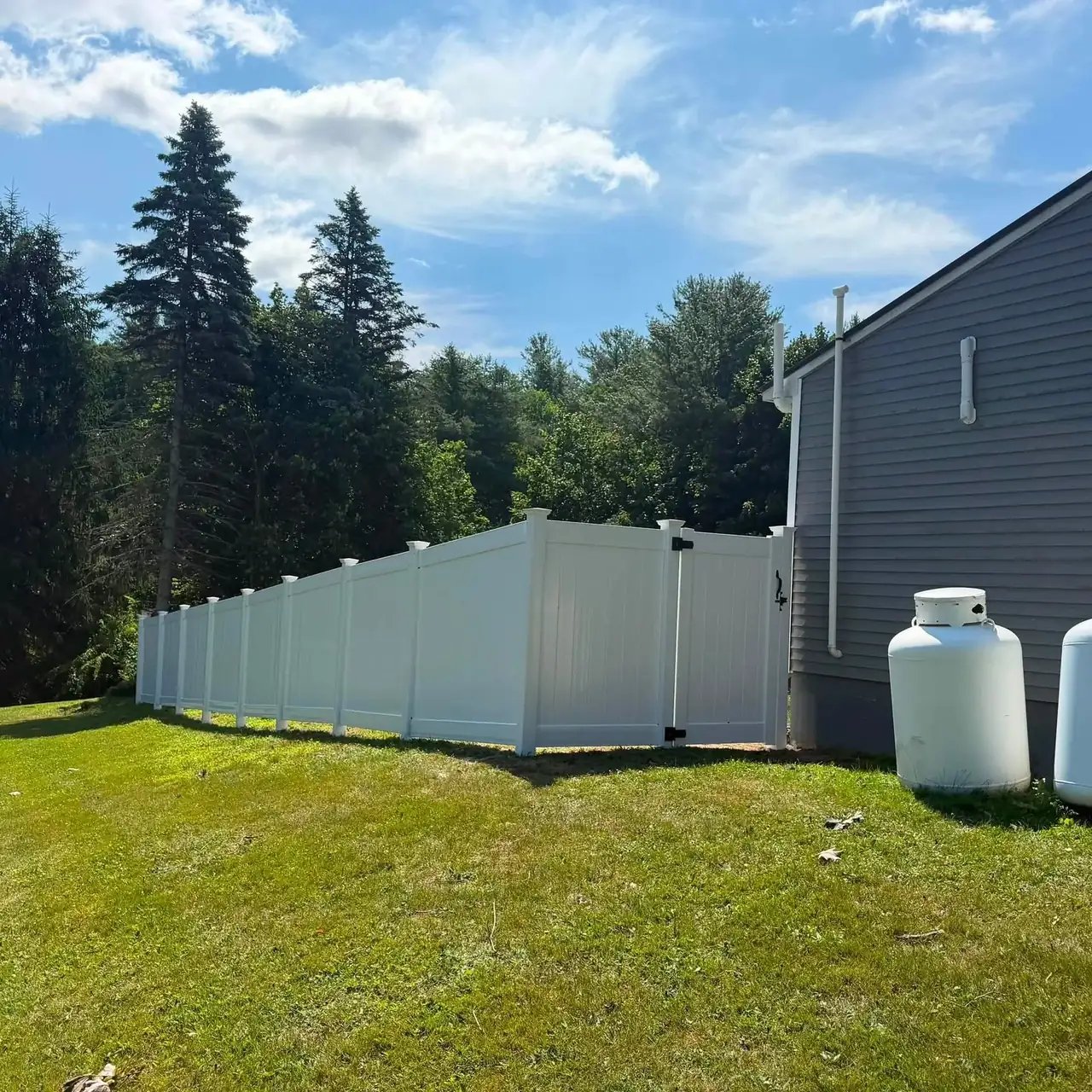 White vinyl privacy fence and gate along a lawn